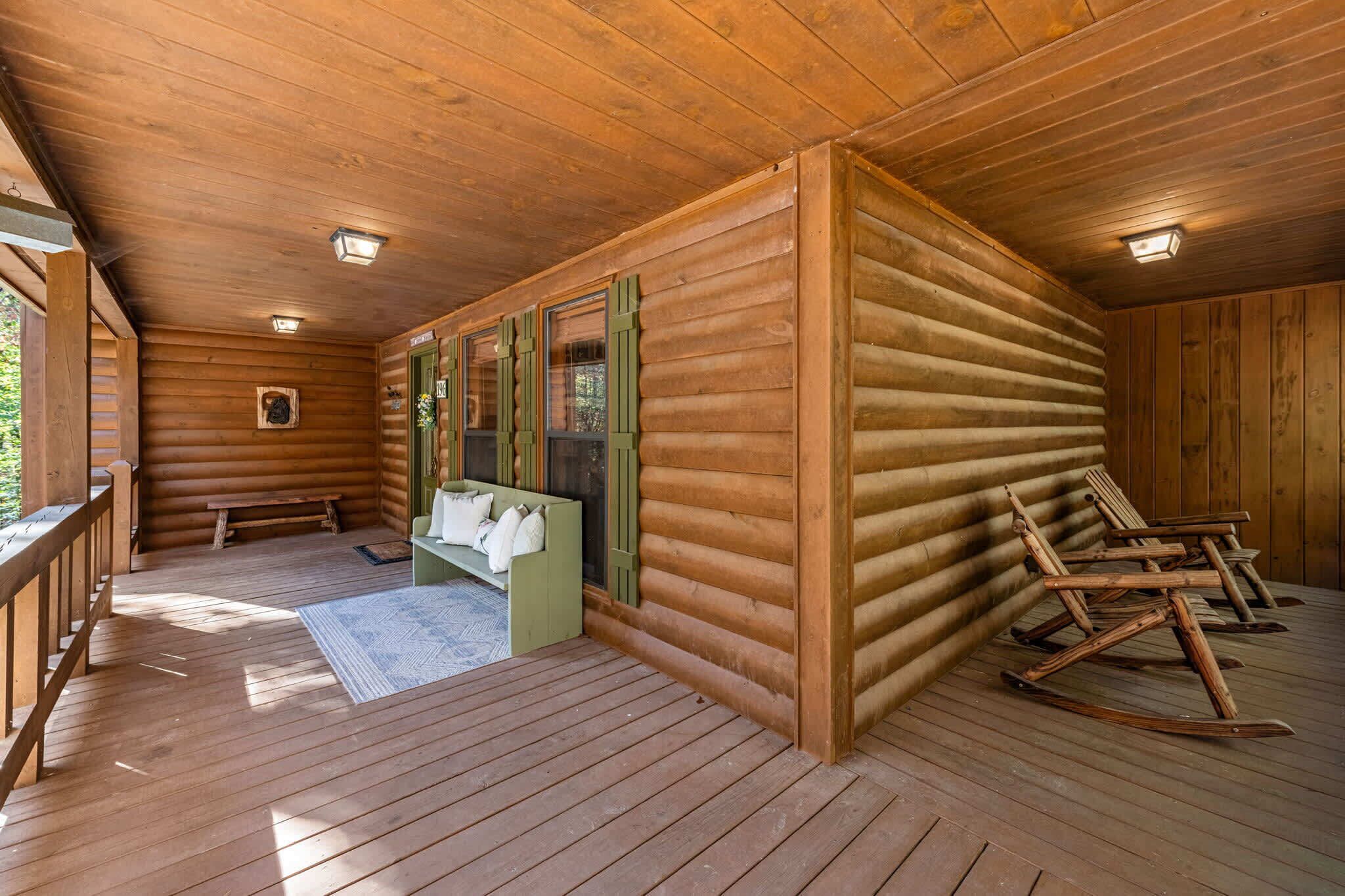 A log cabin interior with a wooden deck, a bench, a rocking chair, and a sofa.