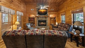 A cozy cabin interior with a fireplace, wooden walls, a sofa, and a television. - Dogwood Lodge - Hot Tub, Near Kerith House Winery (Morganton)