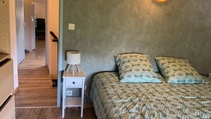 Ein Schlafzimmer mit einem Bett, einem Nachttisch mit Lampe und einer Wandleuchte.