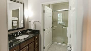 A bathroom with a sink, mirror, and a glass-enclosed shower.