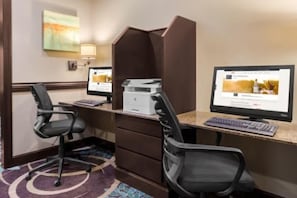 Habitación de hotel con escritorio, dos monitores, una impresora y una silla.