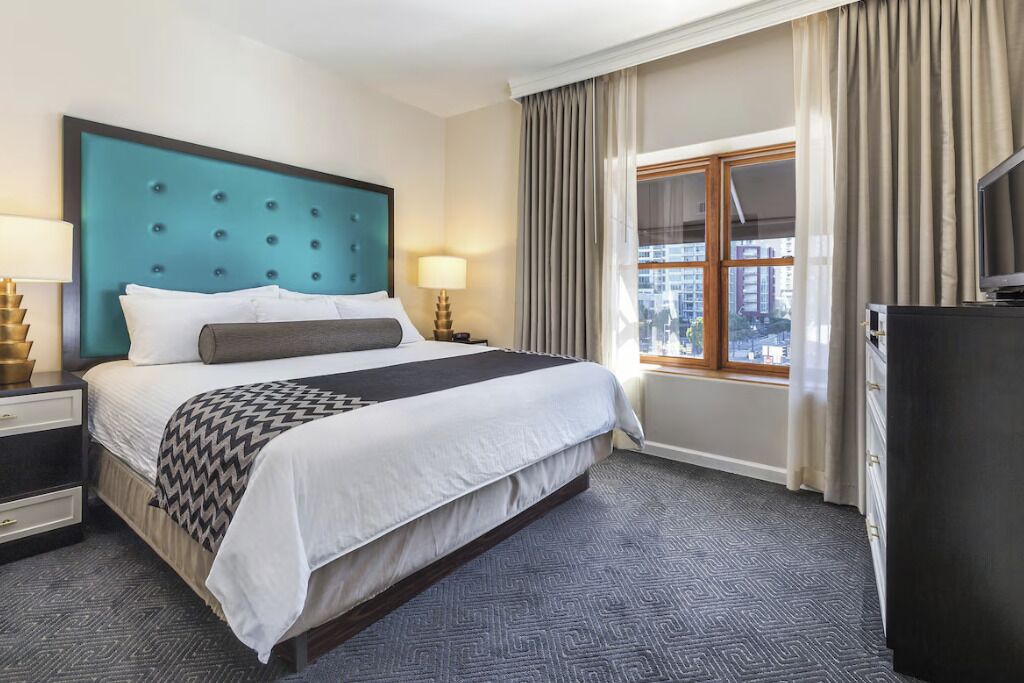 Een hotelkamer met een groot bed, uitzicht op de stad, een televisie en een bureau met een lamp.