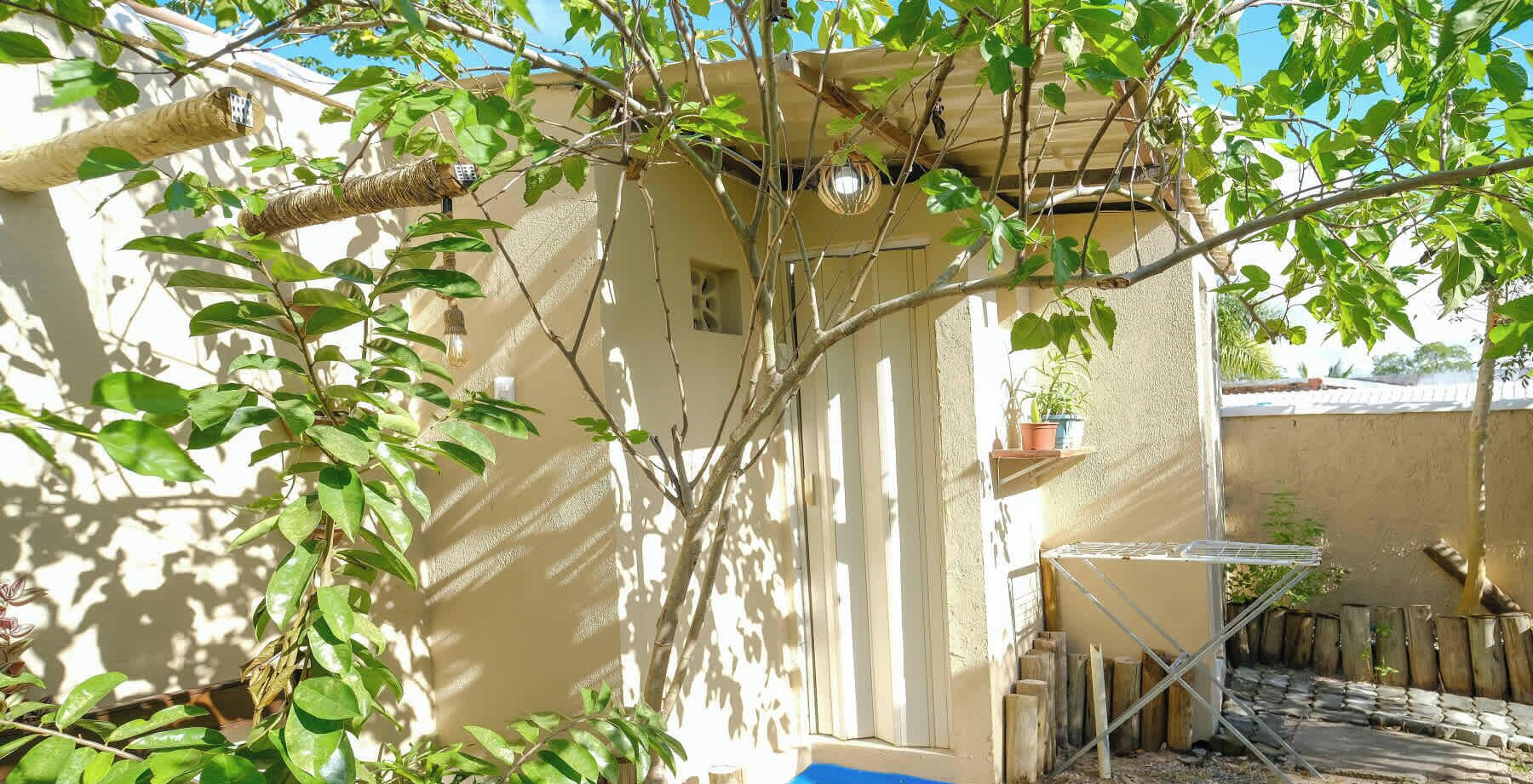A building with a tree in front, a small window, and a metal structure to the right.