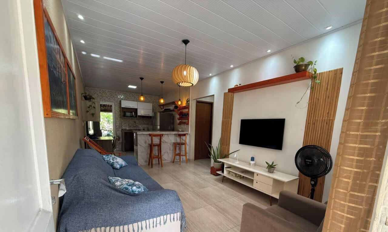 A modern living room with a sofa, TV, and a dining area with a kitchen in the background.