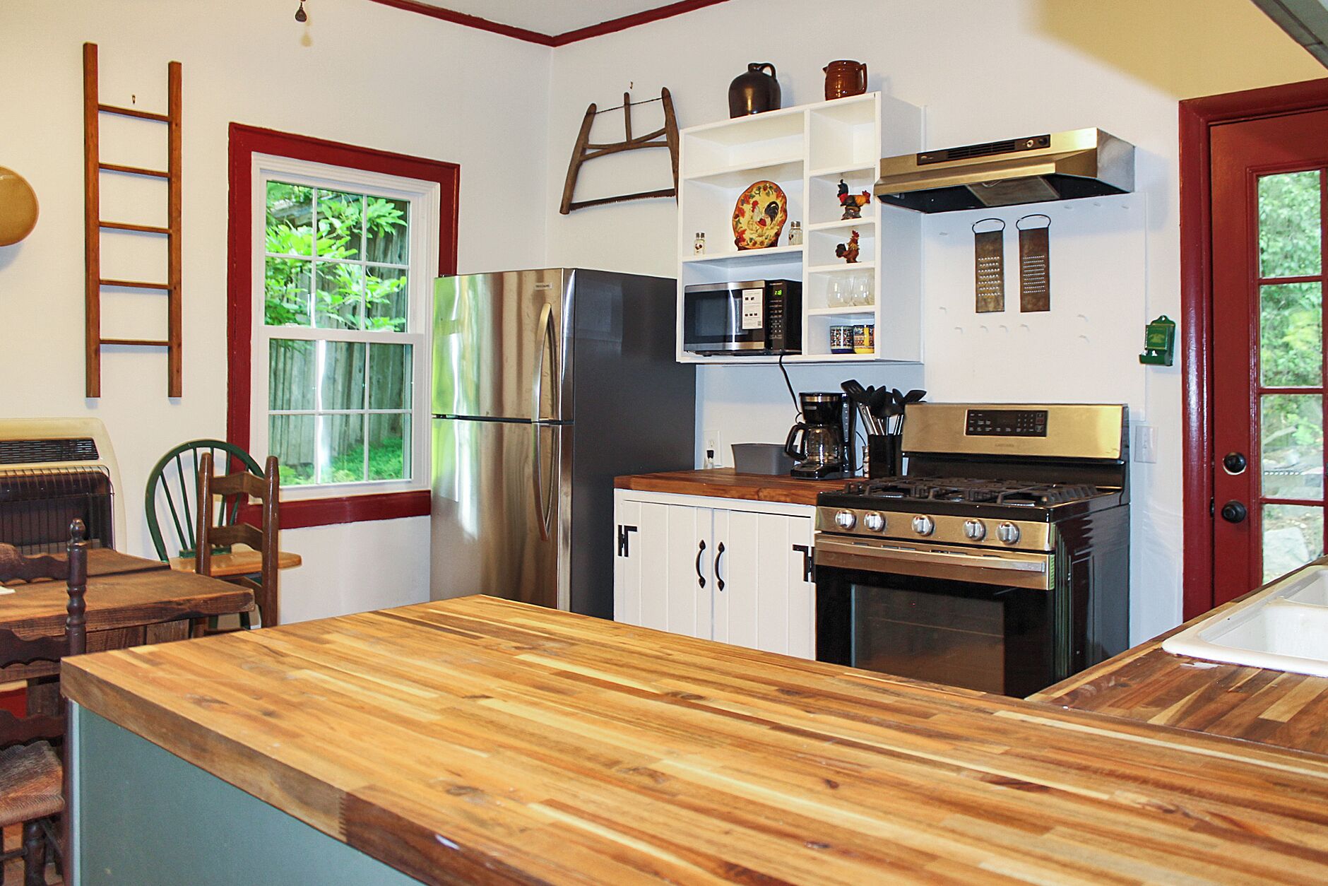 A kitchen with a wooden countertop, stainless steel appliances, and white cabinetry.
