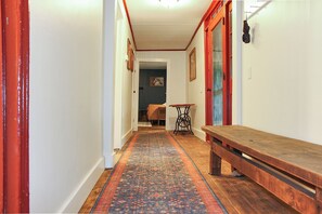 A hallway with a patterned carpet, a wooden bench, and a sewing machine.
