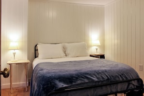 Une chambre à coucher avec un lit, deux tables de chevet avec des lampes et une porte.