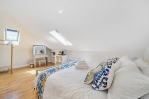 Ein Schlafzimmer mit einem Bett, einem Schminktisch mit Spiegel und einem Dachfenster.