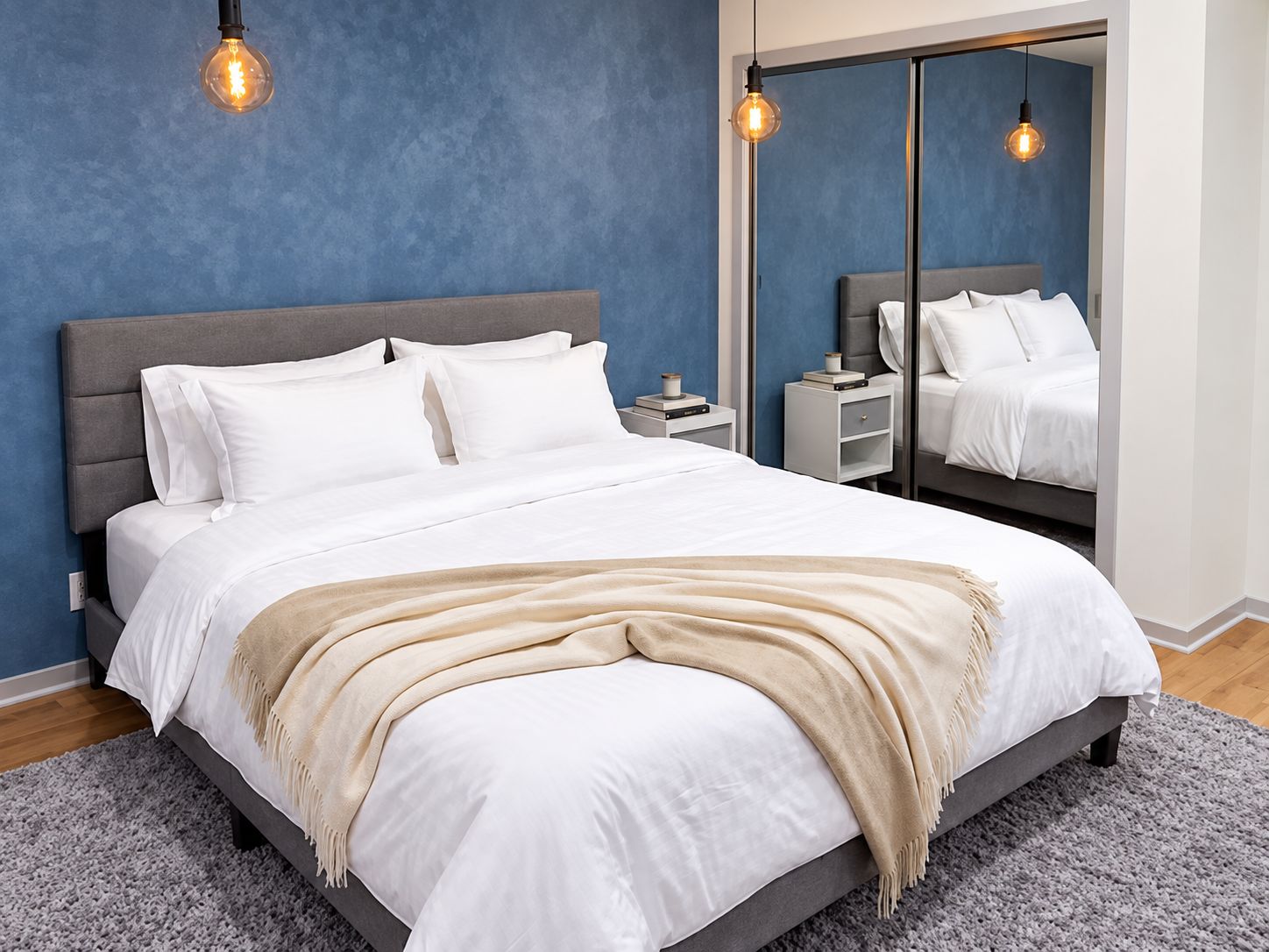 A modern bedroom with a large bed, bedside tables, and a mirror.
