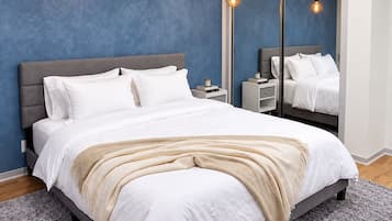 A modern bedroom with a large bed, bedside tables, and a mirror.