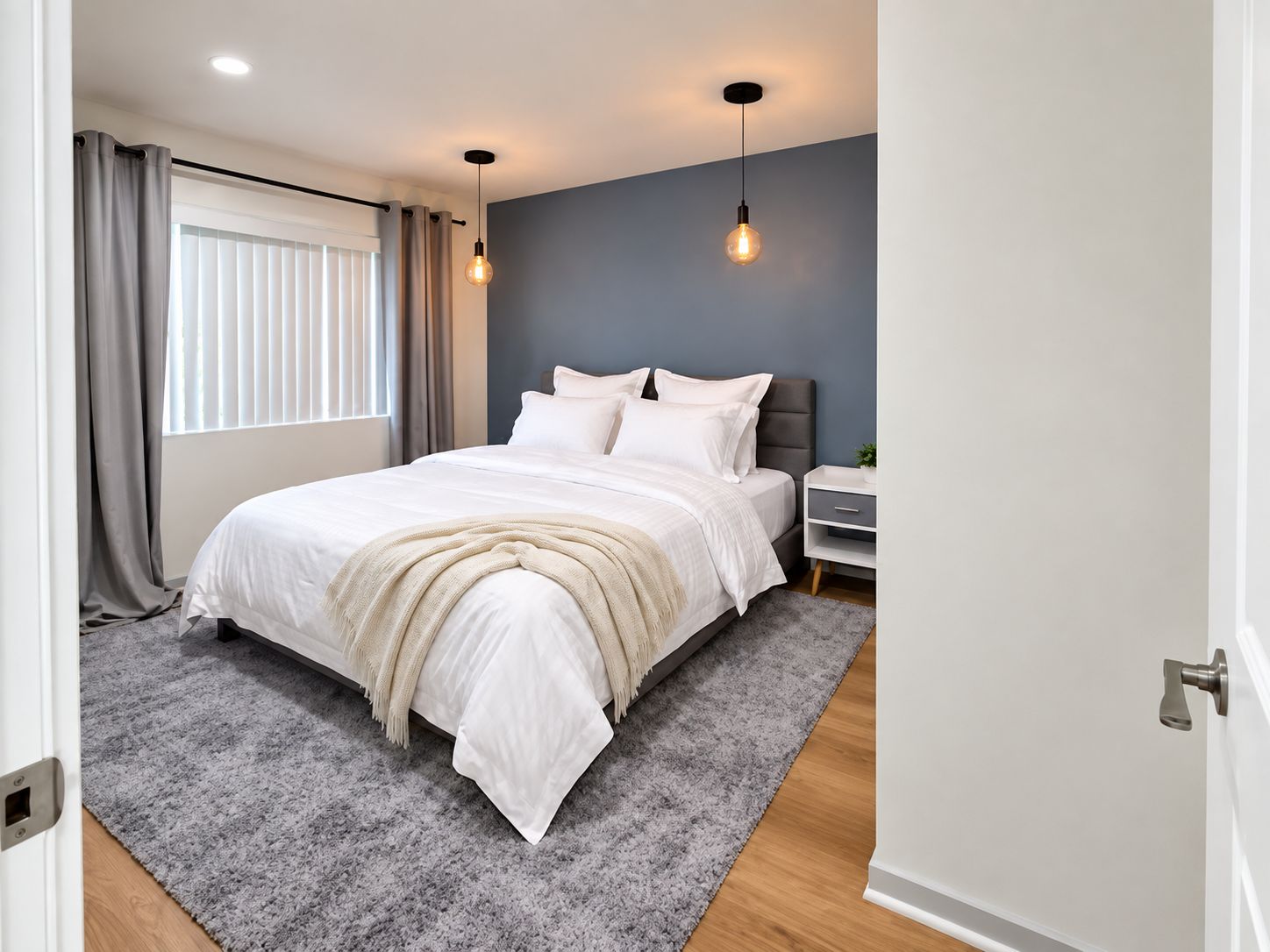 A bedroom with a bed, bedside table, and a window with curtains.