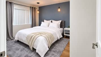 A bedroom with a bed, bedside table, and a window with curtains.