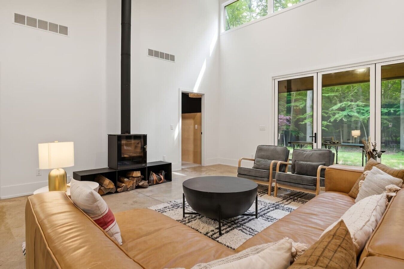 Un salon moderne doté d’une cheminée, de sièges confortables et d’une grande fenêtre offrant une vue sur l’extérieur.