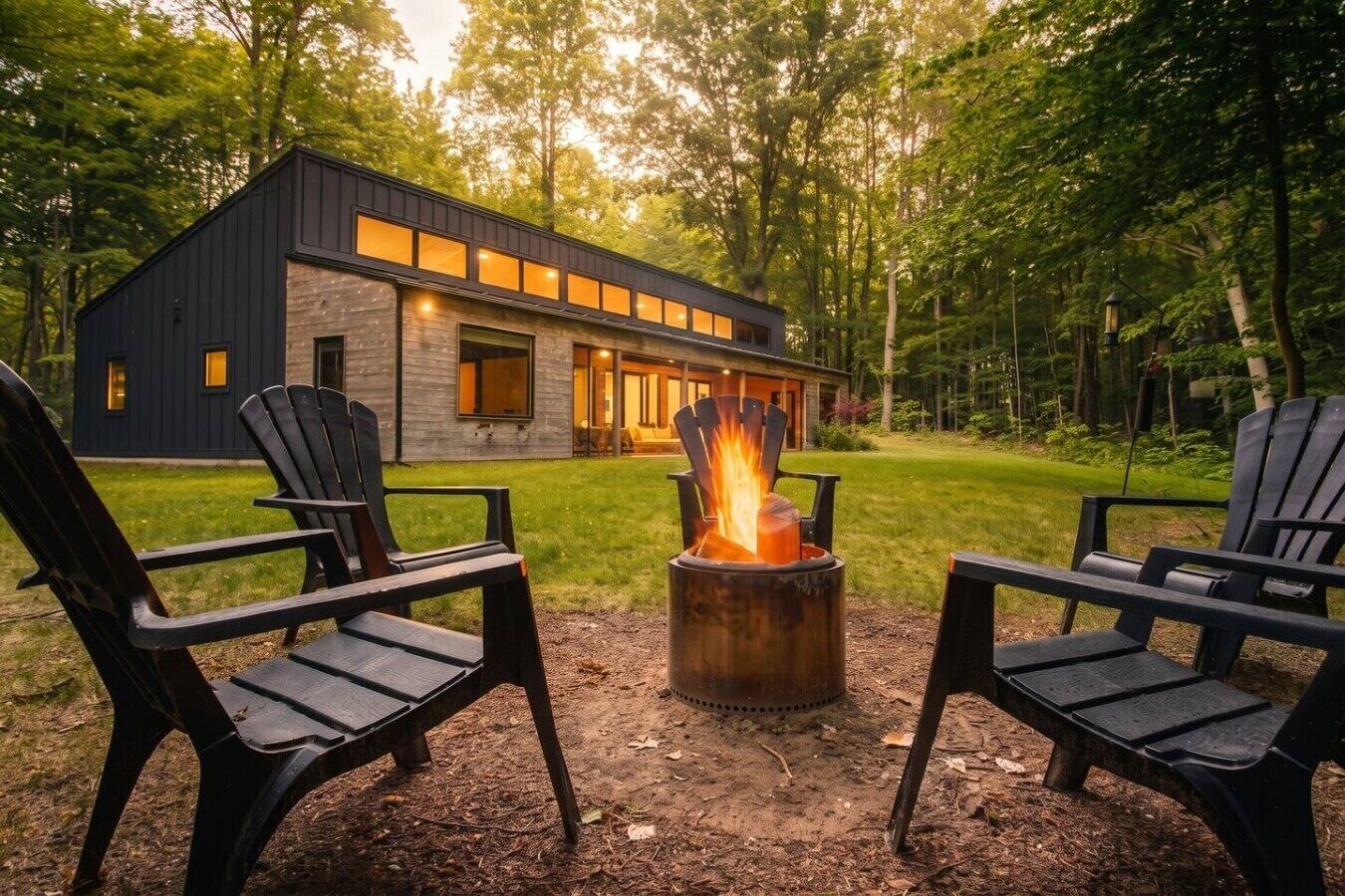 A modern house with a fire pit and two Adirondack chairs in the yard.