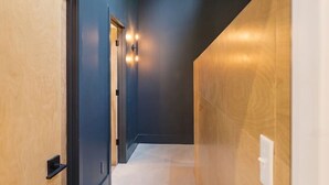 Un pasillo con paredes de madera y piso alfombrado, que conduce a una puerta con interruptor de luz.