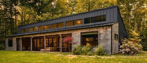 A modern two-story house with a covered porch, large windows, and a well-maintained lawn.