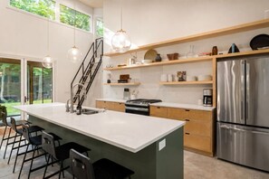 Eine moderne Küche mit einer großen Kochinsel, Edelstahlgeräten und einer Treppe zu einer oberen Ebene.