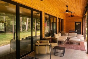 Un interior moderno con techo de madera, puertas correderas de vidrio, un conjunto de sofás y una mesa de comedor.