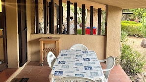 Una terrazza esterna con tavolo e sedie, una panchina in legno e un muro in pietra.
