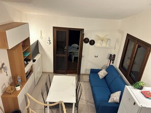 A compact living space with a kitchenette, a dining area, and a sofa. - Adorable 2-bedroom house with AC in Costa Paradiso (Trinita d'Agultu and Vignola)