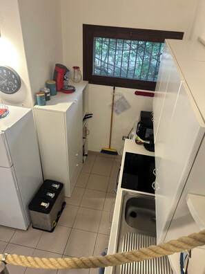 A compact kitchen with a refrigerator, stove, sink, and a window with a view of trees. - Adorable 2-bedroom house with AC in Costa Paradiso (Trinita d'Agultu and Vignola)