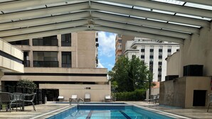 Ein Swimmingpool mit klaren blauen Fliesen, umgeben von Liegestühlen und einem überdachten Bereich.