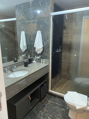 A modern bathroom with two sinks, a large mirror, and a shower area. - Functional apartment opposite Congonhas Airport. (São Paulo)