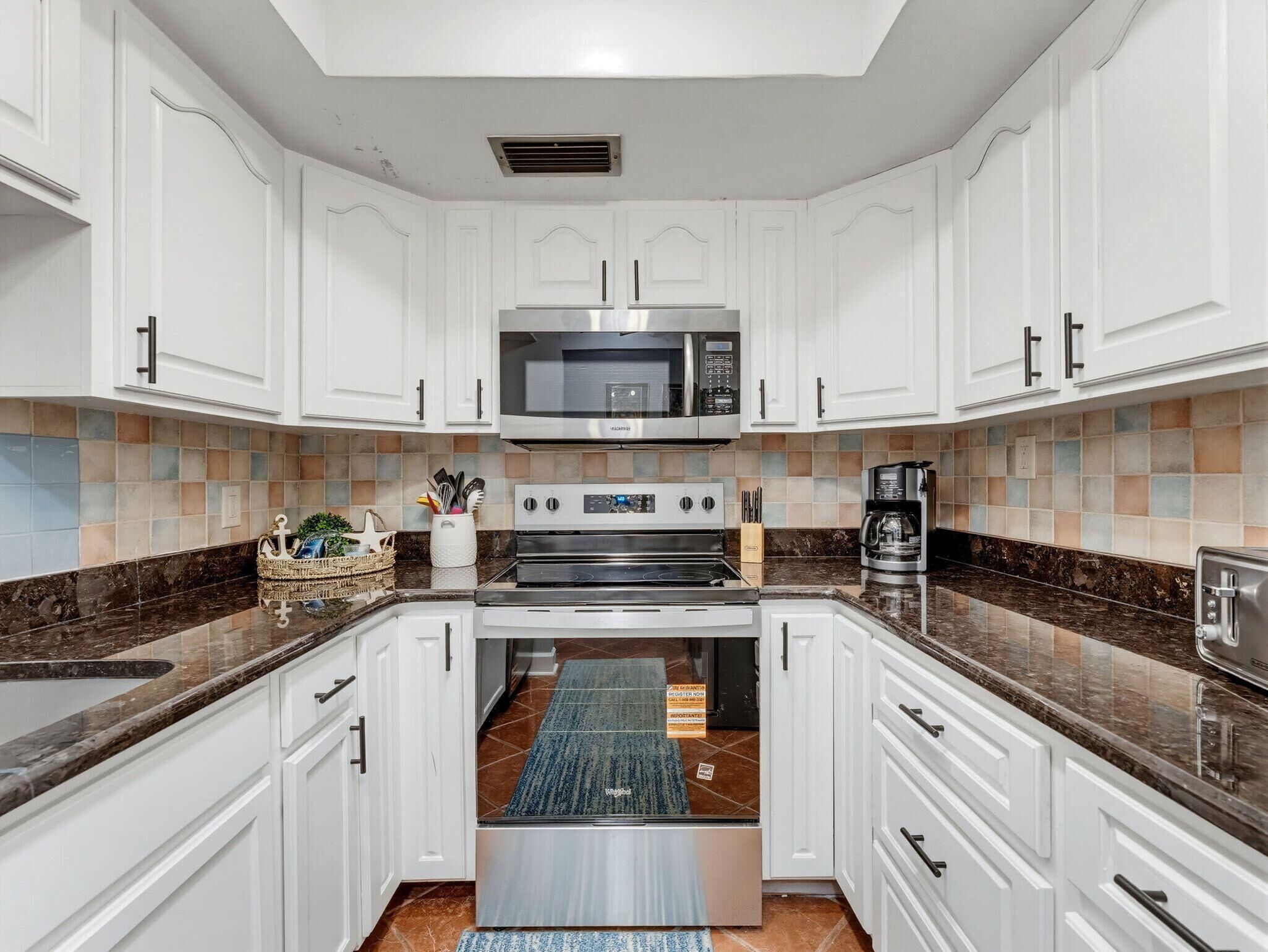 A modern kitchen with white cabinetry, a stainless steel microwave, and a built-in oven.