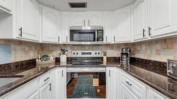 A modern kitchen with white cabinetry, a stainless steel microwave, and a built-in oven.