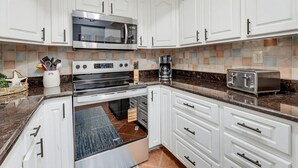 Una cocina moderna con armarios blancos, electrodomésticos de acero inoxidable y un salpicadero de azulejos.