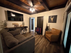 A cozy living room with a sofa, a chair, a wooden table, and a decorative bear sculpture. - Fantastic 5-bedroom cabin in North Fork perfect for relaxing getaways (North Fork)
