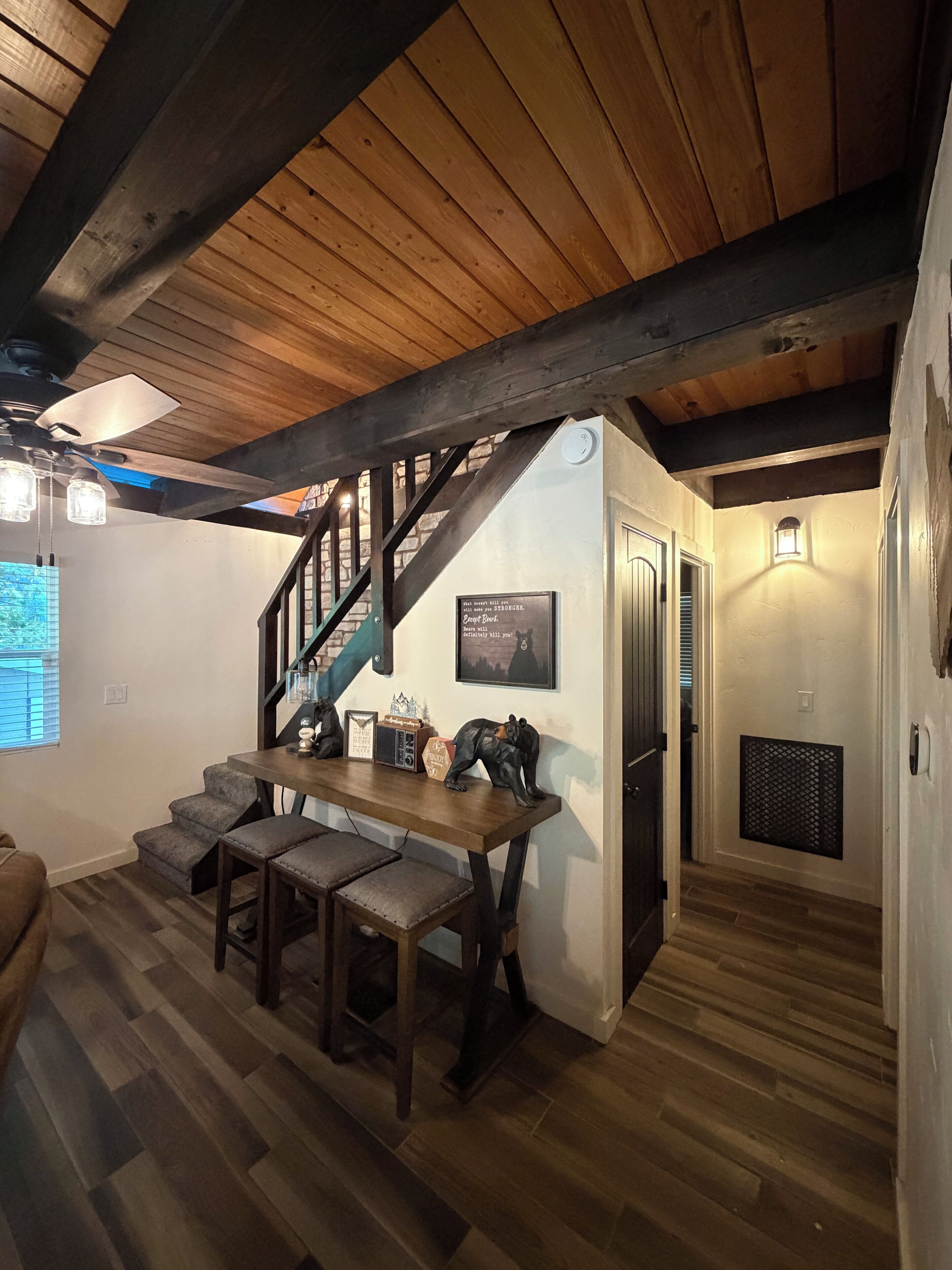 A wooden interior with a staircase, a dining area with a table and chairs, and a kitchen area.