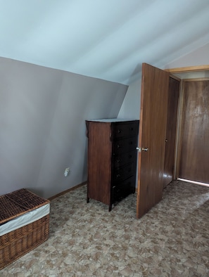 A room with a wooden dresser, a wicker basket, and a closed door.