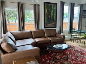 A living room with a brown leather sofa, a round coffee table, and a red patterned rug.