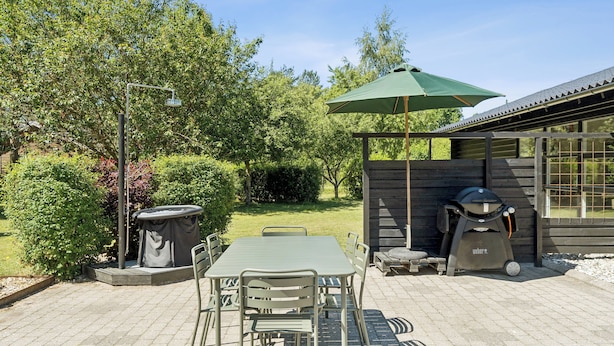 An outdoor patio with a table and chairs, a barbecue grill, and a covered seating area. - Luxury retreat surrounded by nature (Rønde)