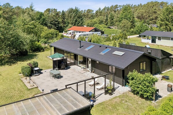 Een woonhuis met een ruime patio, een overdekte zithoek en een schuin dak met dakramen.
