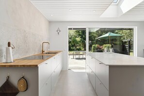 A modern kitchen with a central island, a dining area with outdoor seating, and a view of a garden.