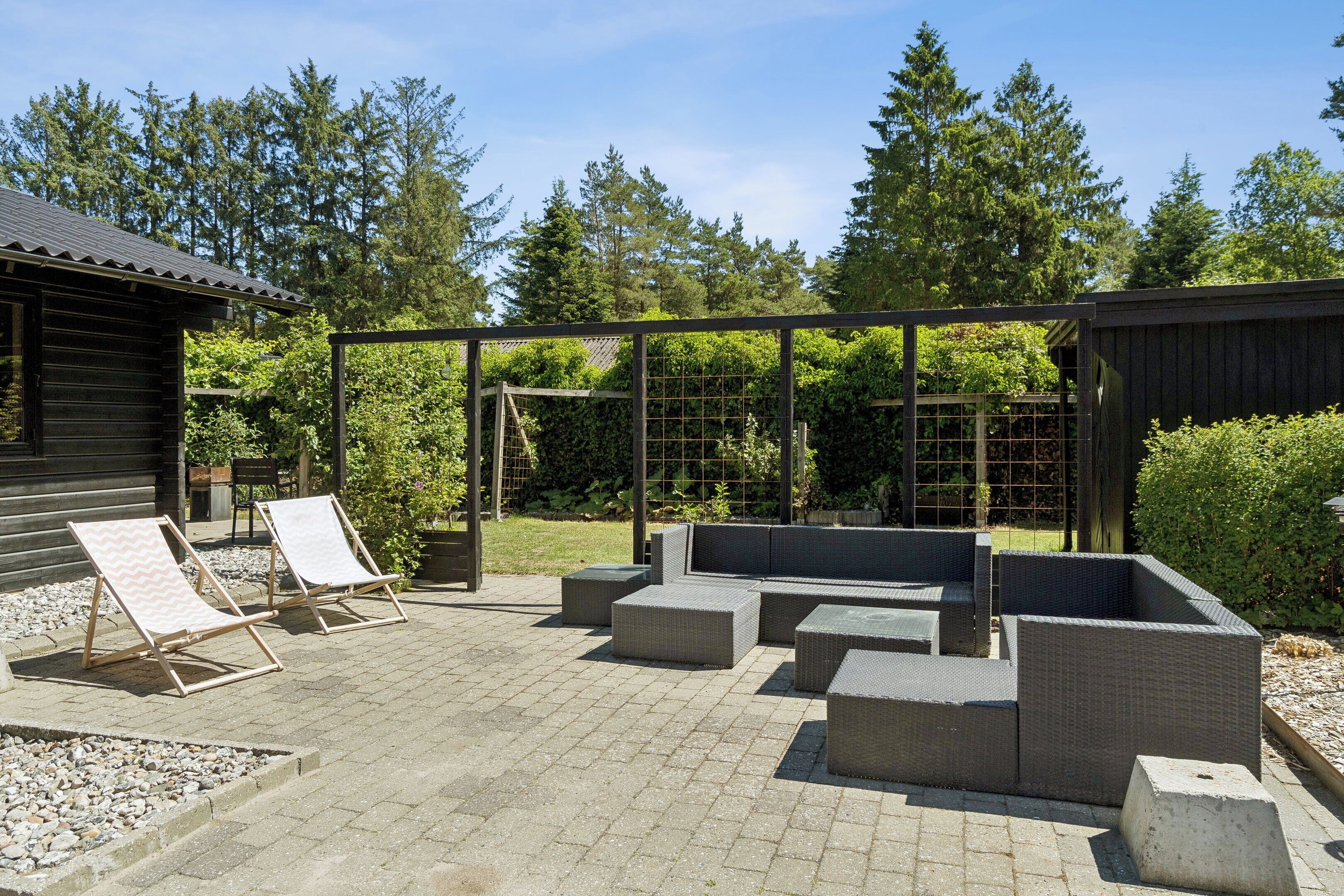 An outdoor seating area with wicker furniture and a pergola structure.