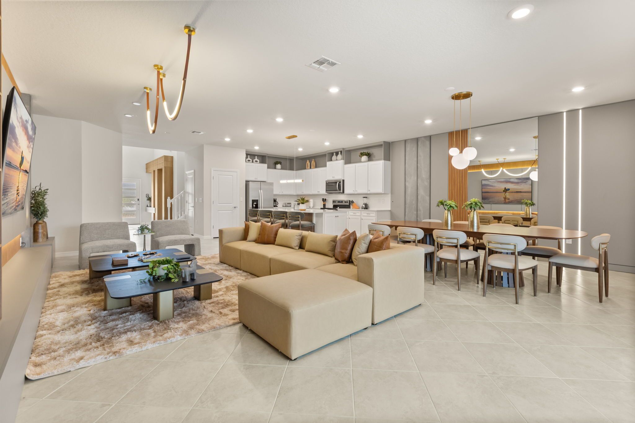 Uma sala de estar moderna com um sofá seccional, uma área de jantar com mesa redonda e uma cozinha com armários brancos.