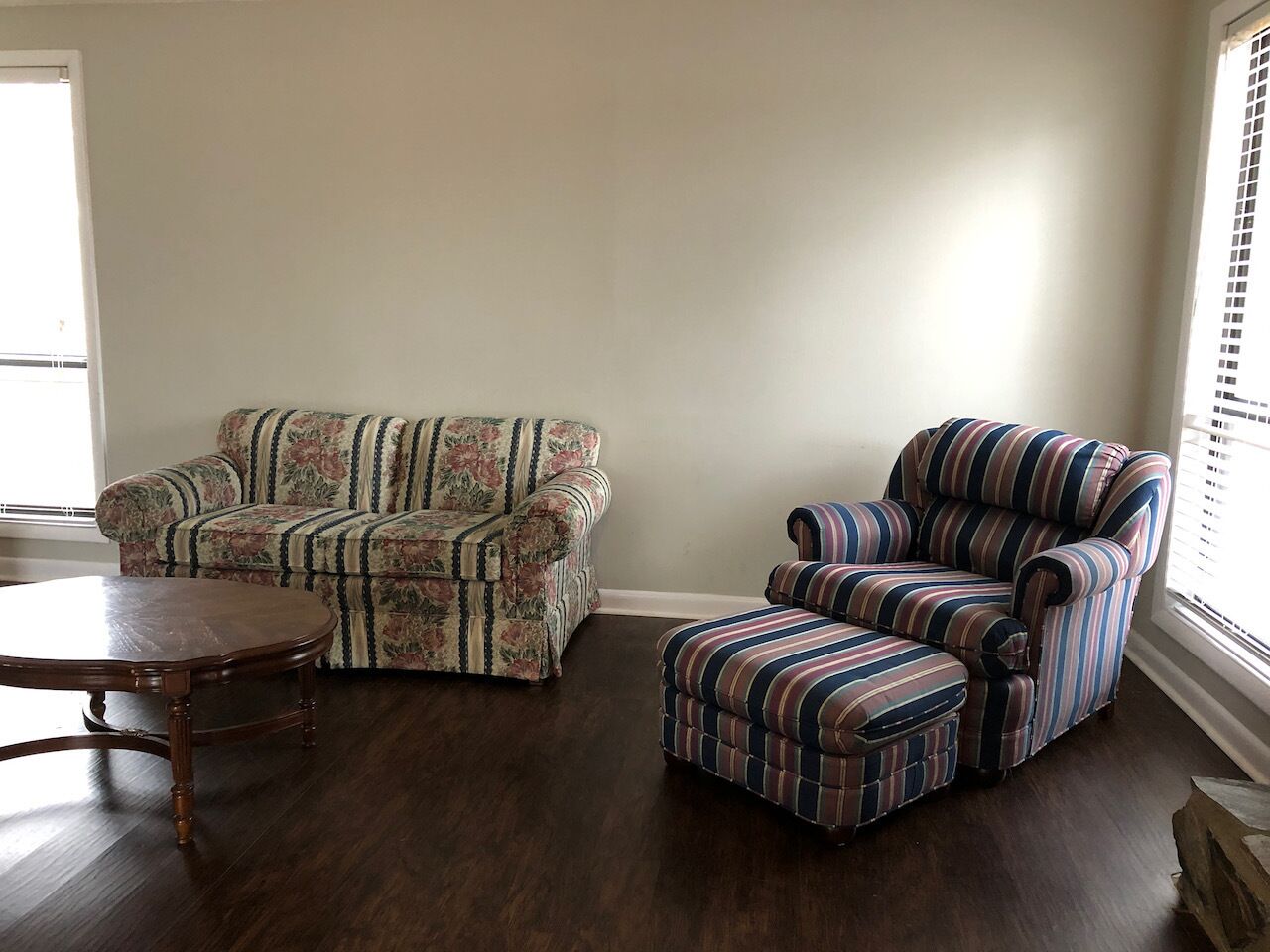 A living room with a floral sofa, a striped armchair, and a wooden coffee table.