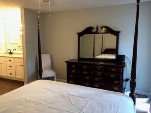 A bedroom with a four-poster bed, a dresser with drawers, a chair, and a large mirror. - gorgeous house central to shopping, military  base and hospitals. Best schools (Fayetteville)