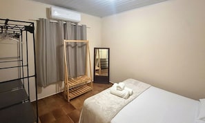 A bedroom with a bed, a wardrobe, a mirror, and an air conditioning unit. - House w/ Balcony & Covered Garage Dbaa0105 (Pirenópolis)
