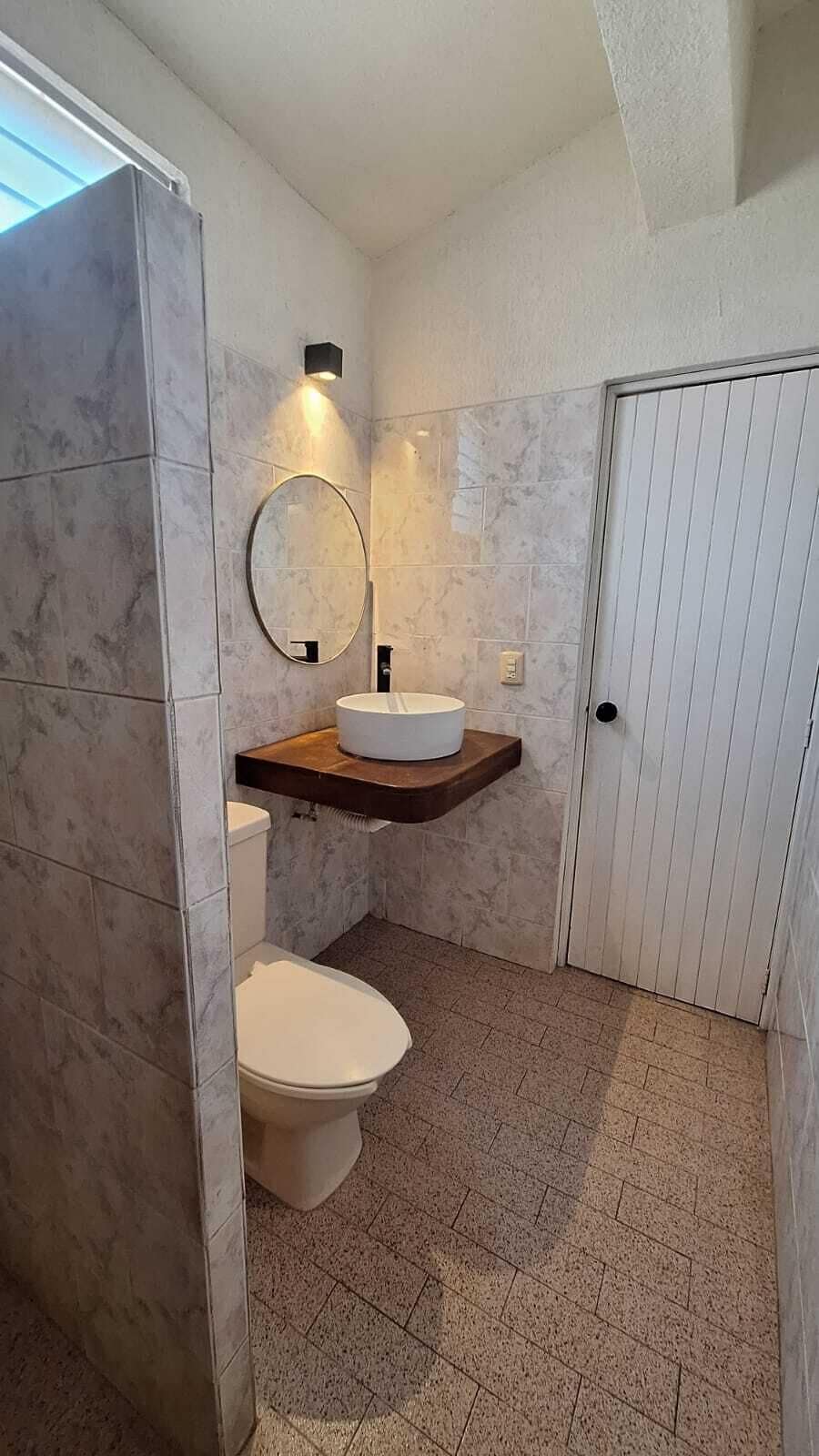 Kylpyhuone, jossa on wc, peilillä varustettu pesuallas ja suihkutila.