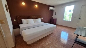 Habitación de hotel con una cama grande, una mesita y una ventana.