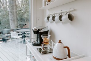 Eine moderne Küche mit einer Kaffeemaschine, einem Wasserkocher und einer Glaskaraffe auf einer weißen Arbeitsplatte.