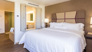 A hotel room with a large bed, a bedside table, a nightstand, a mirror, and a bathroom visible through an open door. - Luxury 1BR Villa at Westin Los Cabos Resort with Ocean Views & Spa Retreat (San José del Cabo)