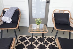Two wicker chairs with black cushions and a small glass table with a plant, set on a patterned rug. - New Cozy Home minutes from downtown, med center & NRG (Houston)
