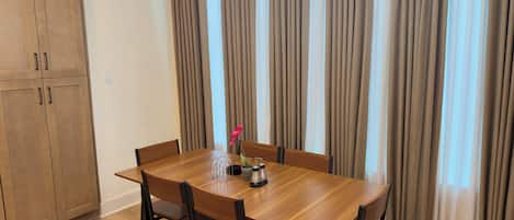 A dining area with a wooden table and chairs, a chandelier, and curtains.