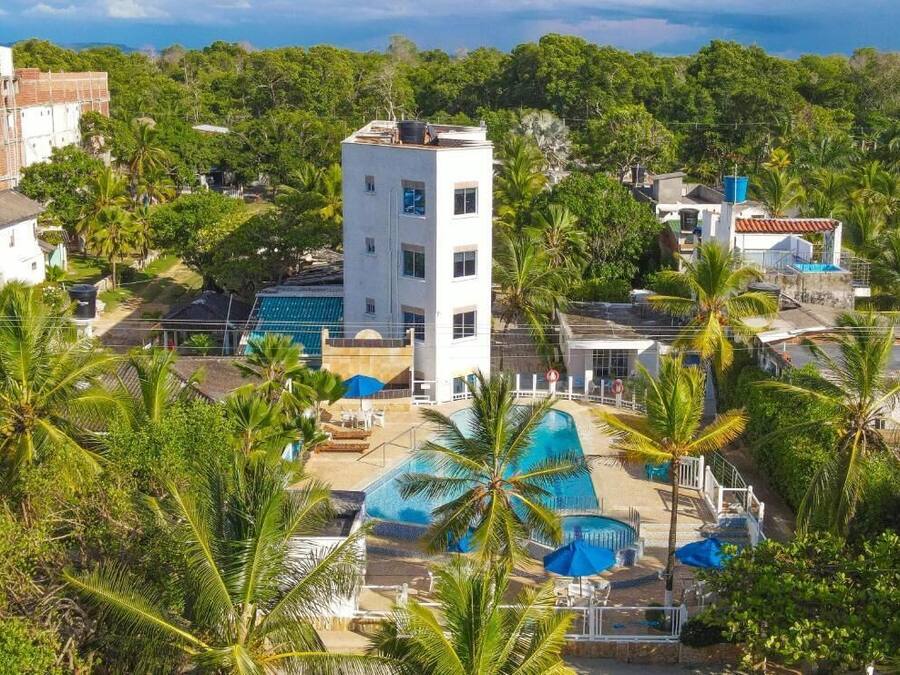 A resort with a swimming pool, palm trees, and a white building with multiple windows.