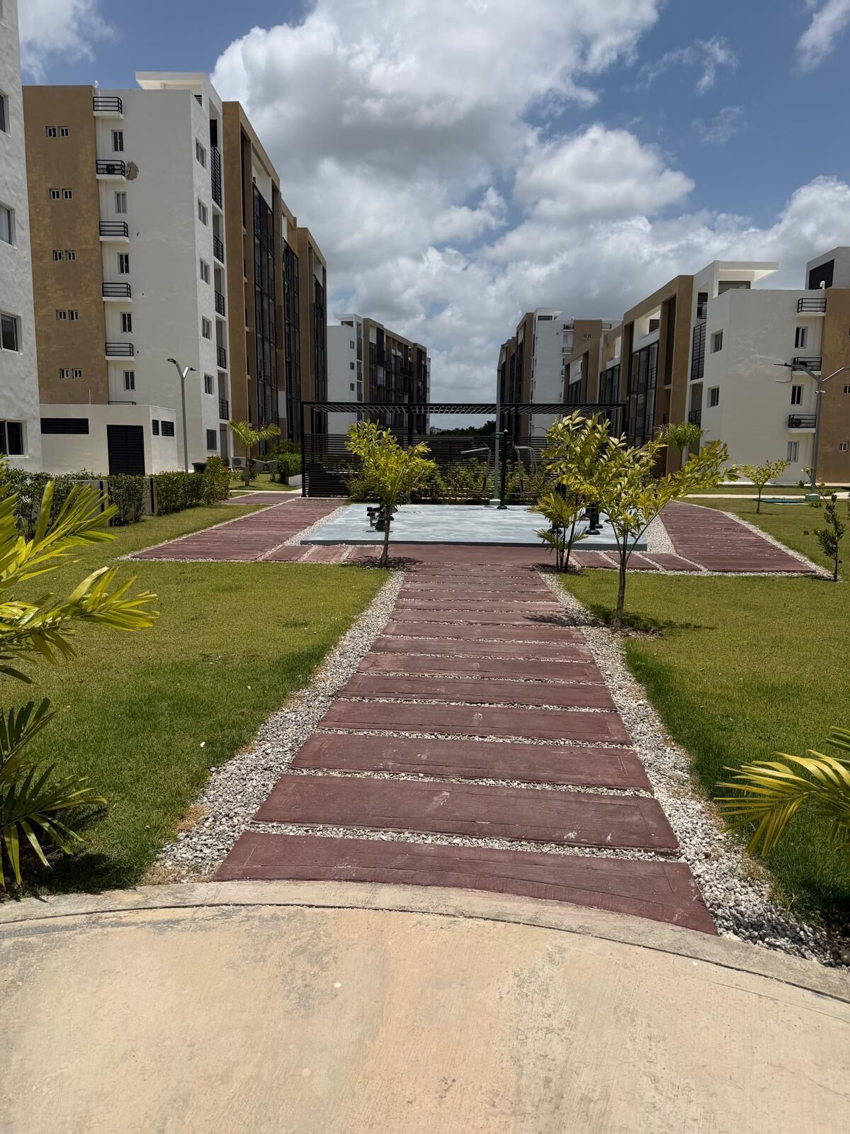 A pathway leading to a residential building complex with multiple floors and balconies.